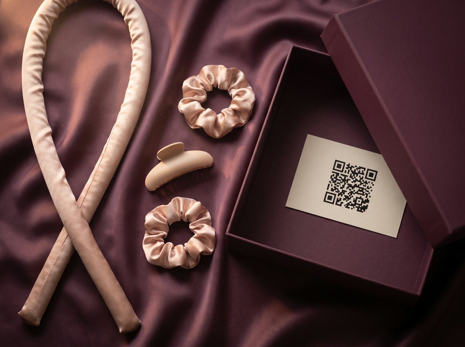 Le bigoudi, les deux chouchous, la pince et la boîte WaveCharm posés sur du satin prune